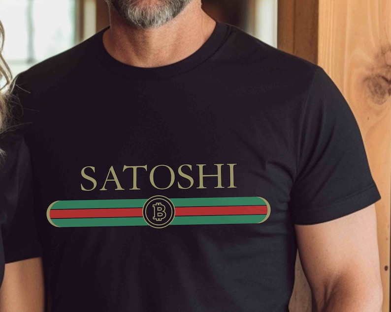 May include: Black t-shirt with a gold "SATOSHI" text and a green, red, and white stripe with a gold Bitcoin symbol.