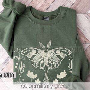 May include: A green sweatshirt with a white print of a moth and flowers. The text "color: military green" is printed below the image.