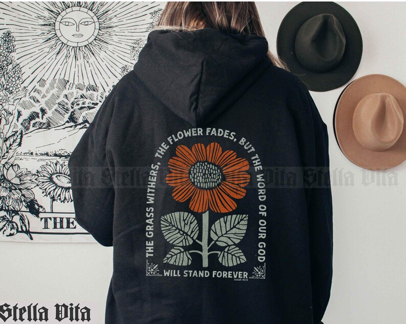 May include: Black hooded sweatshirt with a graphic print of a sunflower and the text "The grass withers, the flower fades, but the word of our God will stand forever".