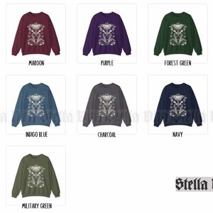 May include: A selection of crew neck sweatshirts with a white floral design on the front. The sweatshirts are available in maroon, purple, forest green, indigo blue, charcoal, navy, and military green.