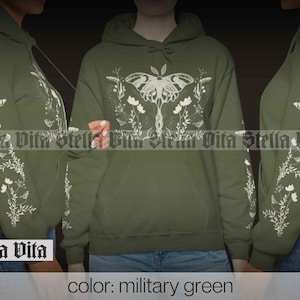 May include: A military green hoodie with a white print of a moth and floral design. The text "Stella Vita" is printed on the bottom left corner of the hoodie.
