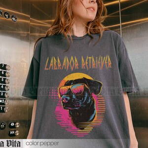 Puede incluir: Una camiseta gris oscura con un gr&aacute;fico de un Labrador Retriever con gafas de sol y el texto "Labrador Retriever" en una fuente estilizada.