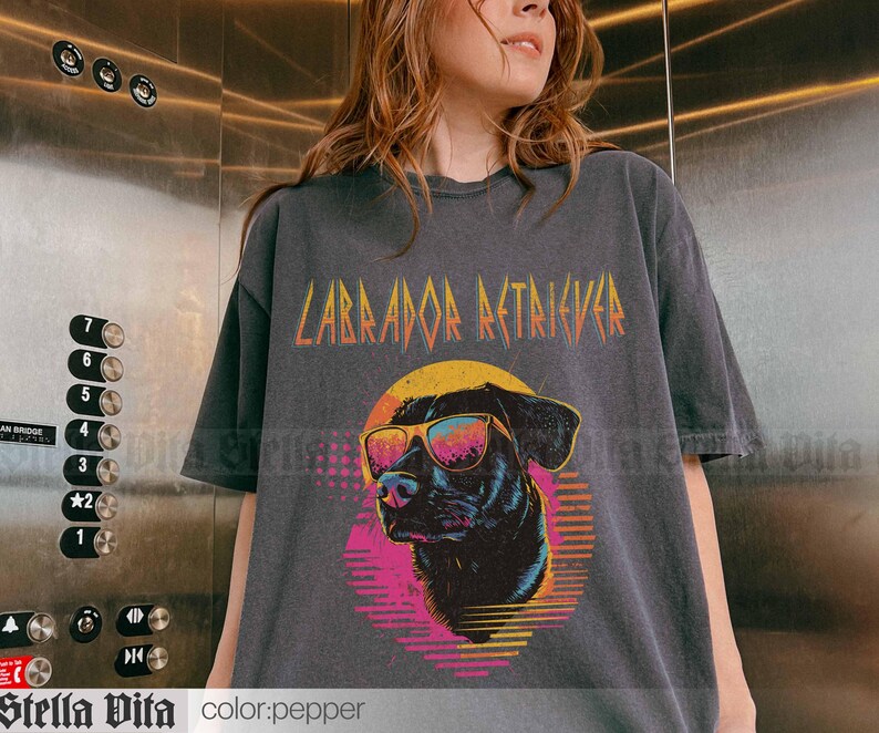 Puede incluir: Una camiseta gris oscura con un gr&aacute;fico de un Labrador Retriever con gafas de sol y el texto "Labrador Retriever" en una fuente estilizada.