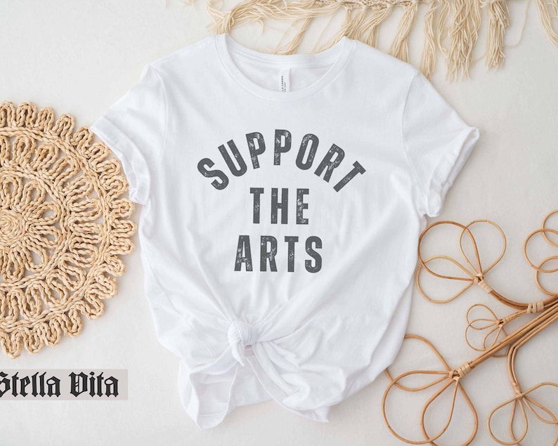 May include: White t-shirt with the text "Support the Arts" printed in gray on the front.