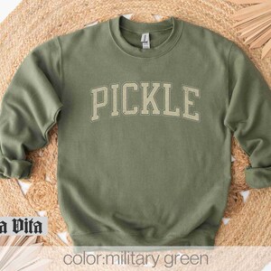 May include: A green sweatshirt with the word "PICKLE" printed in a vintage collegiate style font.