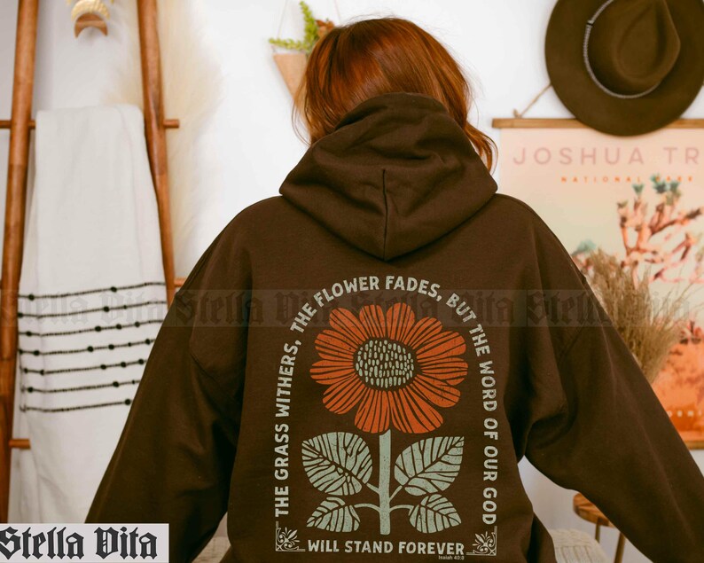 May include: Brown hooded sweatshirt with a graphic print of a sunflower and the text "The grass withers, the flower fades, but the word of our God will stand forever."