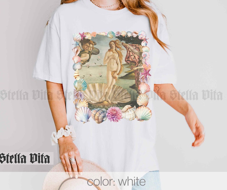 Puede incluir: Camiseta blanca con un gr&aacute;fico de la pintura El nacimiento de Venus rodeado de conchas.