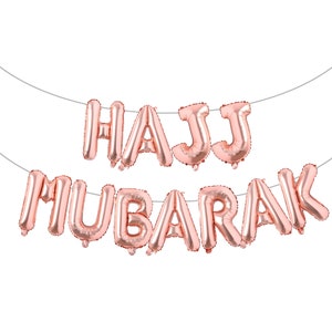 May include: Rose gold foil balloon letters spelling "HAJJ MUBARAK" hanging on a string.