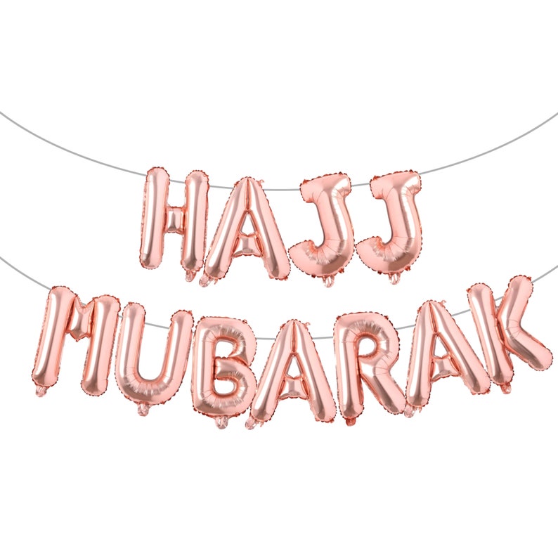 May include: Rose gold foil balloon letters spelling "HAJJ MUBARAK" hanging on a string.