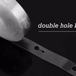 May include: A roll of clear plastic balloon strip with double holes for attaching balloons. The strip is rolled up and a section is unrolled to show the double holes. The text "double hole balloon strip" is printed on a black background.