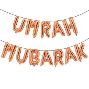 May include: A gold foil balloon banner that reads "UMRAH MUBARAK".