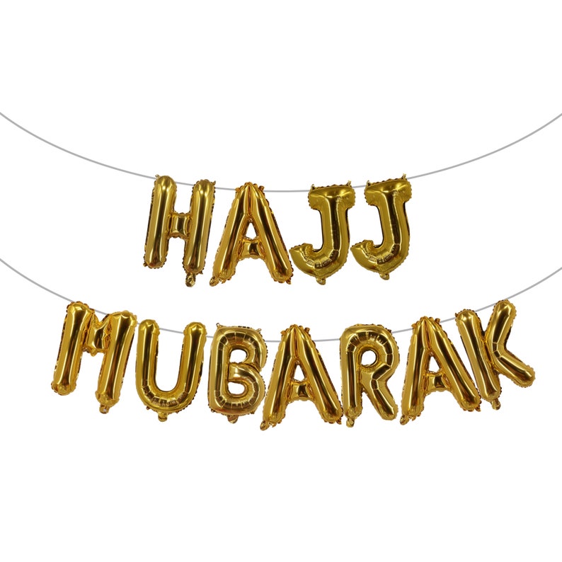 May include: Gold foil balloon letters spelling "HAJJ MUBARAK" hanging on a string.
