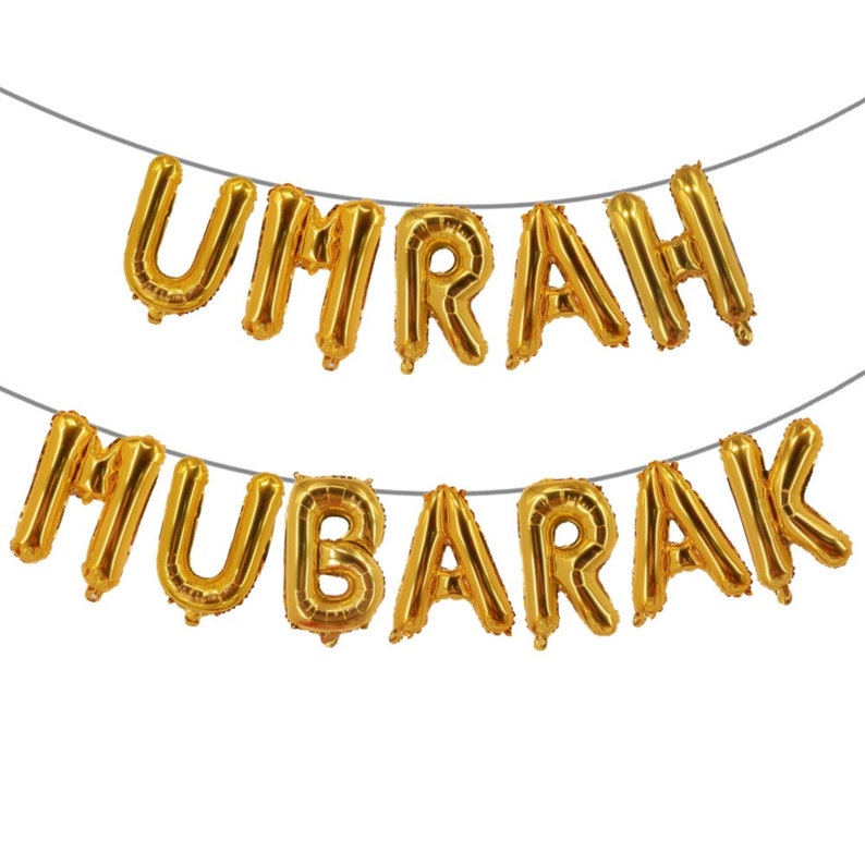 May include: Gold foil letter balloons spelling "UMRAH MUBARAK" strung together on a white background.