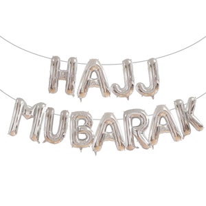 May include: Silver foil balloon letters spelling "HAJJ MUBARAK" hanging on a string.