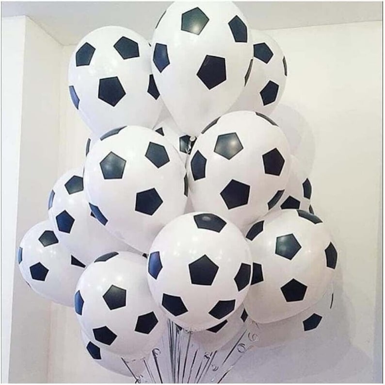 May include: A bunch of white and black soccer ball balloons. The balloons are arranged in a cluster, with some overlapping.