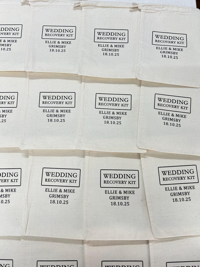 May include: A collection of off-white cotton drawstring bags, each printed with a black rectangular border containing the text WEDDING RECOVERY KIT, followed by the names ELLIE & MIKE GRIMSBY and the date 18.10.25 in a clean sans-serif font.