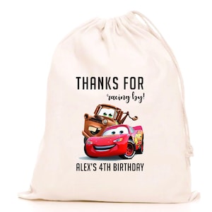 Puede incluir: Una bolsa de cordón de color crema con Rayo McQueen y Mate de la película Cars. La bolsa tiene el texto "THANKS FOR racing by!" y "ALEX'S 4TH BIRTHDAY" impreso en negro.