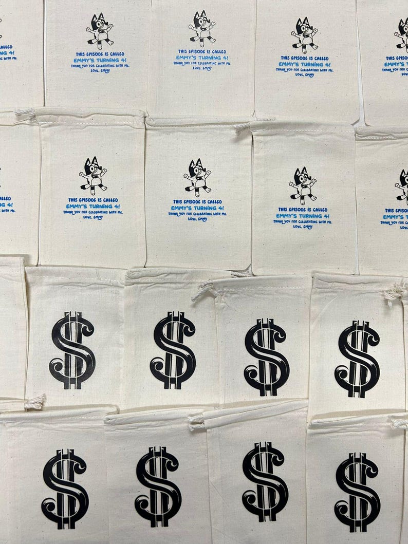 May include: A collection of off-white drawstring cotton bags. Some bags feature a black cartoon dog graphic with blue text reading: This episode is called Emmy's turning 4! Thank you for celebrating with me. Love, Emmy. Others feature a black dollar sign.