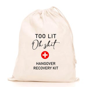 Könnte beinhalten: Ein weißer Beutel mit Kordelzug mit dem Text "Too Lit Oh Shit" und einem roten Kreuzsymbol. Unter dem Text steht "Hangover Recovery Kit".