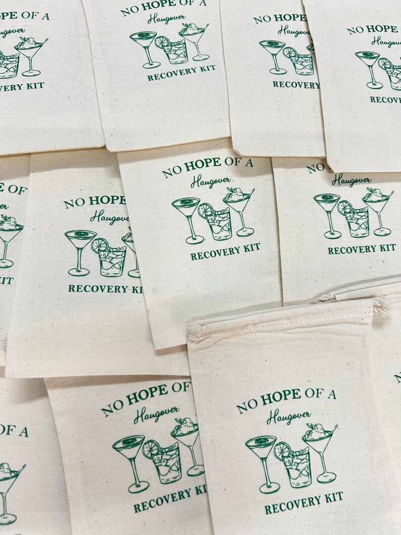 May include: A collection of off-white cotton drawstring bags featuring a green printed graphic of two cocktail glasses and a glass with ice and lime. The text reads NO HOPE OF A Hangover RECOVERY KIT in a mix of serif and script fonts.
