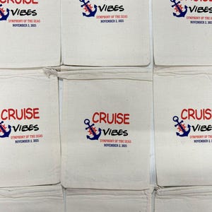 May include: A collection of off-white cotton drawstring bags featuring a printed design with a blue anchor, a red ship wheel, and the text CRUISE VIBES, SYMPHONY OF THE SEAS, and NOVEMBER 2, 2025, arranged in a grid pattern on a flat surface.