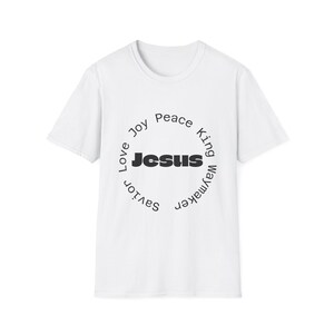 May include: White t-shirt with a circular design. The word "Jesus" is in bold black letters at the centre. The circle includes words such as "Love", "Joy", "Peace", and "Waymaker" in a simple font.