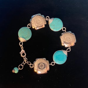 May include: A turquoise and silver bracelet with a decorative clasp. The bracelet features turquoise stones and silver accents.
