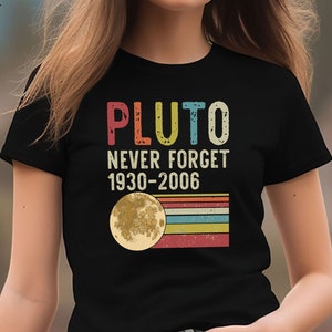 May include: A black t-shirt with a vintage-style graphic that says "Pluto Never Forget 1930-2006" and features a yellow moon with a rainbow stripe design.