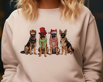 May include: A beige sweatshirt with a Christmas-themed design featuring four German Shepherd dogs wearing festive hats and scarves. The dogs are decorated with Christmas lights.