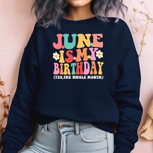 May include: A navy blue sweatshirt with the text "June is my birthday (yes, the whole month)" in colorful letters and flowers.