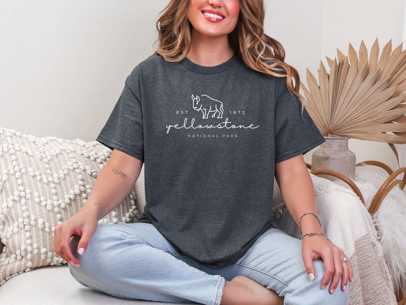 May include: Dark grey t-shirt with the text "Yellowstone National Park" and a bison graphic. The shirt includes the text "Est. 1872". The t-shirt is a comfortable, casual style.