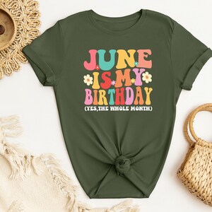 May include: A green t-shirt with the text "JUNE IS MY BIRTHDAY (YES, THE WHOLE MONTH)" in colorful retro lettering with flowers.