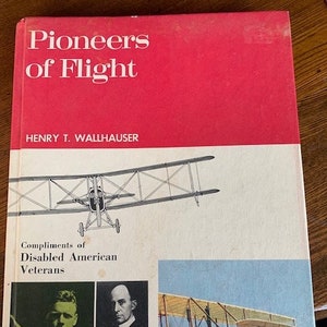 May include: A vintage book titled "Pioneers of Flight" with a red cover and a drawing of an early airplane. The book also features portraits of men and an image of a biplane in flight. The book is a compliment of Disabled American Veterans.