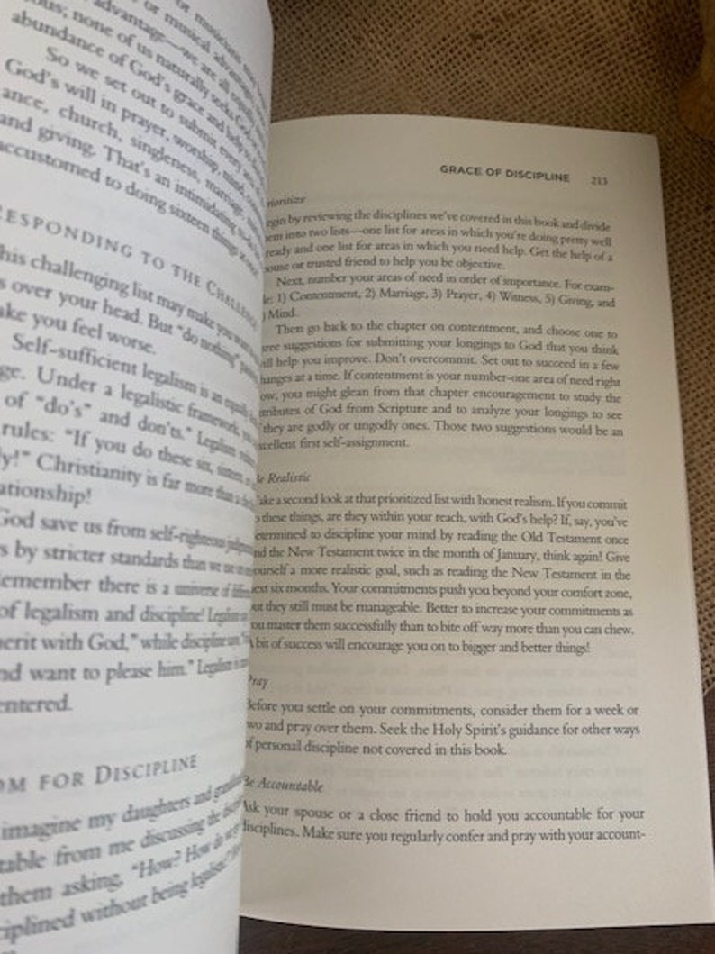 May include: Open book with a white background and black text. The book is titled "Grace of Discipline". The text discusses the importance of discipline and how to prioritize areas of need in life.