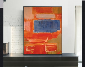 Puede incluir: Pintura abstracta con trazos audaces de naranja, rojo, azul y marrón. La pintura está enmarcada en negro y cuelga de una pared de ladrillo blanco.