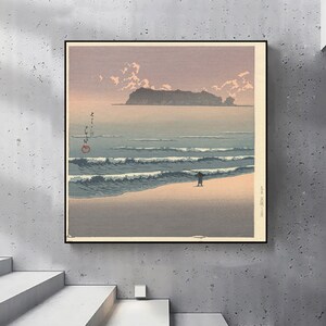 Puede incluir: Una impresión japonesa en madera vintage que representa un paisaje marítimo con una figura solitaria de pie en una playa de arena. El océano es de un azul profundo con olas blancas que rompen en la orilla. En la distancia, se puede ver una pequeña isla contra un cielo rosa pálido.