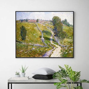 Puede incluir: Una pintura de paisaje enmarcada representa una ladera soleada con un camino sinuoso. La obra de arte presenta una paleta de verdes, amarillos y azules, con árboles y un muro de piedra. La pintura se exhibe en un marco negro.