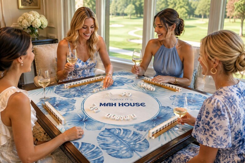 May include: Four people playing Mahjong around a table with a blue and white floral design. The table has the text "Today it's Mah House". Players are holding tiles and glasses of wine, enjoying a social gathering.