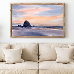 Puede incluir: Una pintura de acuarela de una costa rocosa con un cielo de puesta de sol. La pintura presenta una gran formaci&oacute;n rocosa en el centro, con rocas m&aacute;s peque&ntilde;as y una playa en primer plano. El cielo es una mezcla de rosa, naranja y azul, con algunas aves volando por encima.