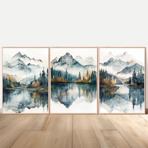 Peut inclure: Ensemble de trois peintures de paysage à l'aquarelle encadrées. Chacune représente une chaîne de montagnes se reflétant dans un lac, avec des arbres verts, dorés et bruns. L'œuvre est encadrée dans un fin métal doré.
