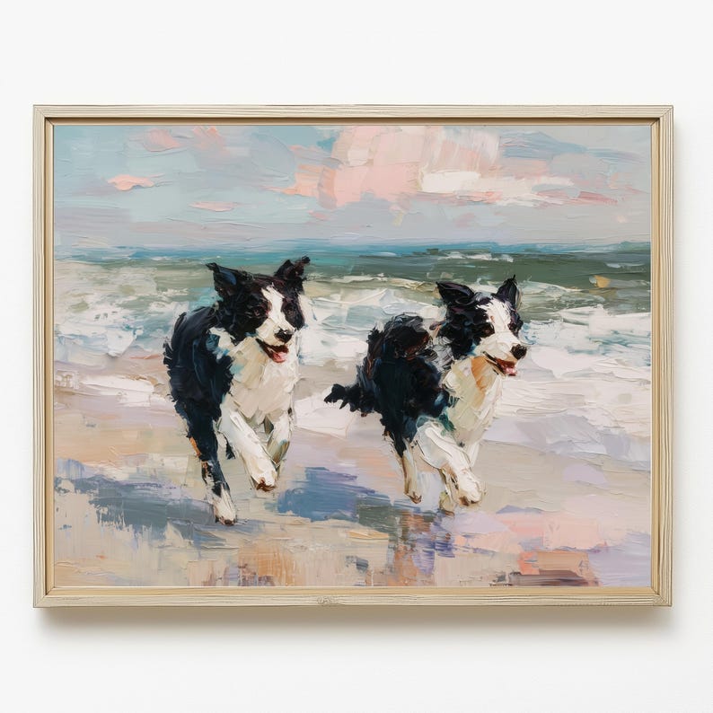 May include: An oil painting in a light wood frame depicting two black and white Border Collie dogs running along a sandy beach. The ocean waves are visible in the background under a soft, pastel-coloured sky with visible brushstrokes throughout.