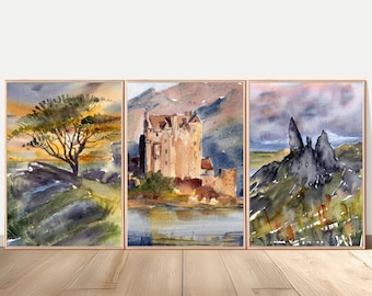 May include: Set of three framed watercolor prints. The artwork depicts a tree, a castle, and a mountain landscape. The color palette includes shades of brown, green, and blue. The frames are a light brown color.