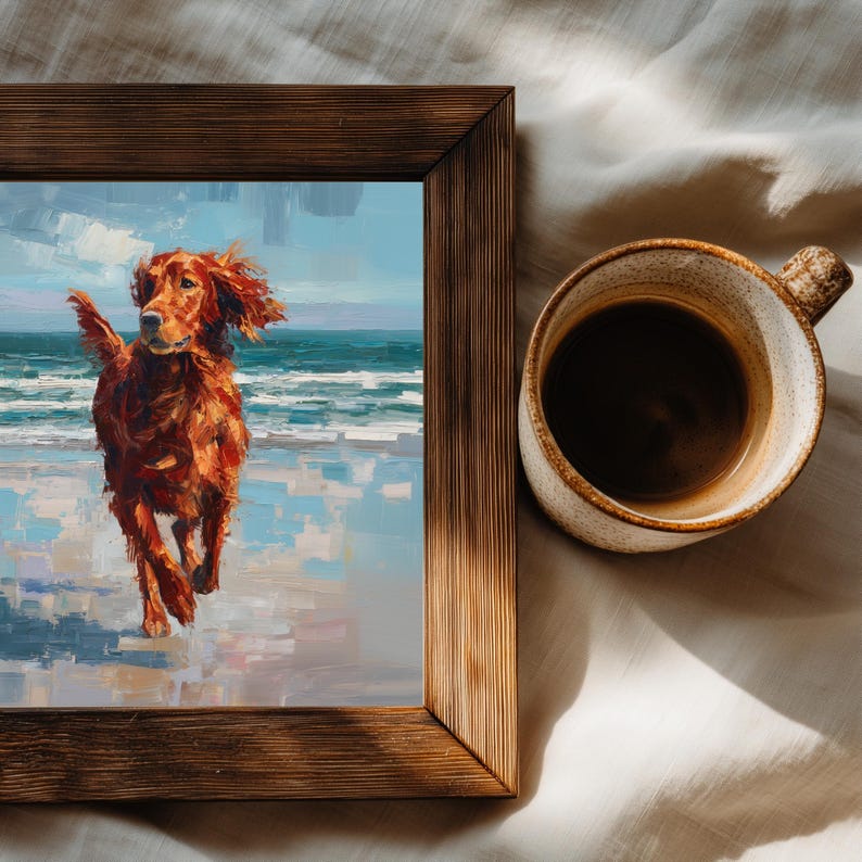 May include: A framed painting of a red Irish Setter dog running on a beach, with a blue sky and ocean in the background. The painting is in a brown wooden frame. A ceramic mug filled with coffee sits next to the frame.