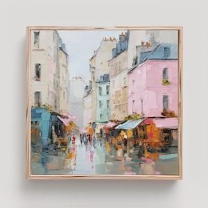 May include: An oil painting in a wooden frame depicting a city street scene with tall buildings in shades of pink, blue, and cream. The street level features storefronts with awnings, small figures of people, and reflections on the ground surface.