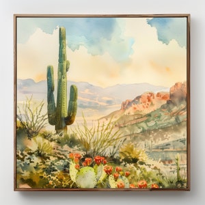 May include: Watercolor painting of a desert landscape featuring a tall green saguaro cactus, prickly pear cacti with red flowers, and distant mountains under a blue and yellow sky. The artwork is framed in a wooden frame.