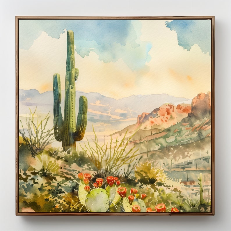 May include: Watercolor painting of a desert landscape featuring a tall green saguaro cactus, prickly pear cacti with red flowers, and distant mountains under a blue and yellow sky. The artwork is framed in a wooden frame.