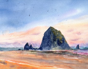 May include: A watercolor painting of a large, dark, jagged rock formation rising from a sandy beach. The sky transitions from blue to soft pink and orange hues at sunset. Small birds are visible in the sky, and the wet sand reflects the light.