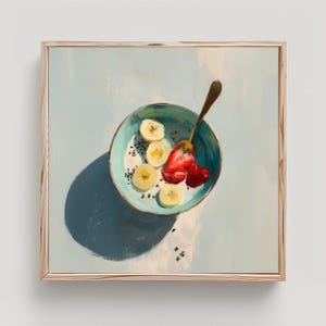 May include: A still-life painting of a breakfast bowl with sliced bananas and strawberries. The bowl is turquoise with a gold spoon. The painting is in a wooden frame and has a blue background.