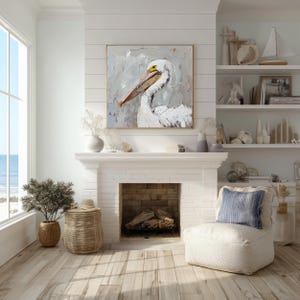Pode incluir: Uma pintura a &oacute;leo quadrada apresentando um pelicano branco com um longo bico laranja e um olho amarelo, feita com pinceladas espessas e texturizadas em tons de branco, cinza e creme, exibida numa moldura dourada fina sobre uma lareira branca.
