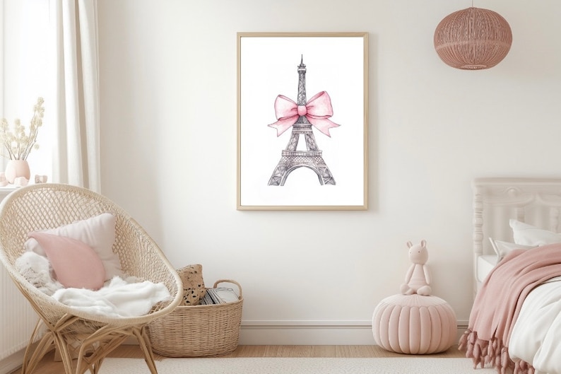 May include: A framed wall art print featuring a detailed black and white sketch of the Eiffel Tower. The tower is adorned with a large, soft pink watercolor-style bow tied around its midsection, centered against a plain white background.